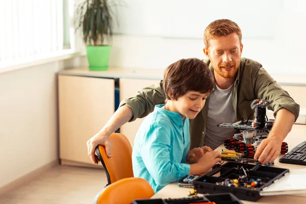 Öğretmeninin yardımıyla bir robot yapan öğrenci.