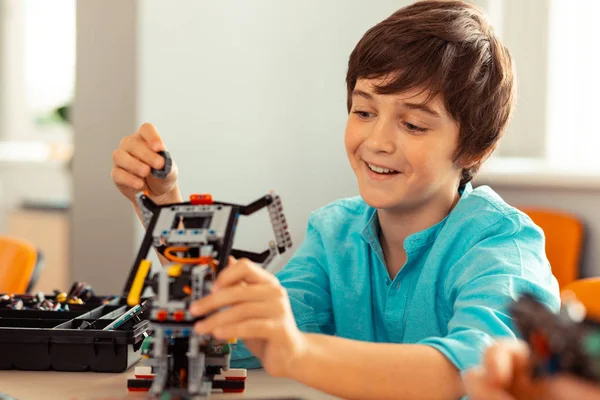 Karmaşık robot üzerindeki işini bitiren çocuk.