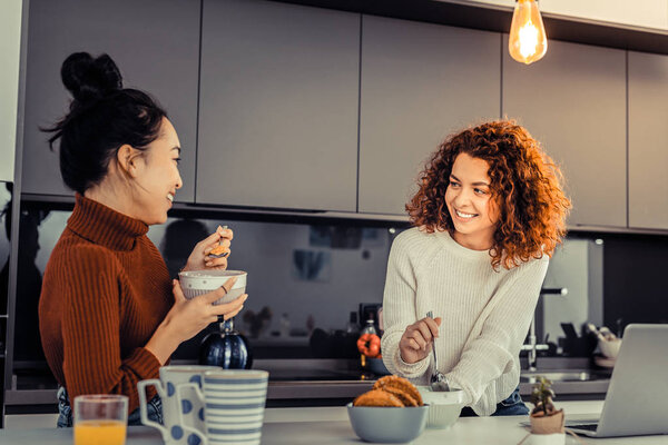 Two friends having breakfast in their kitchen
