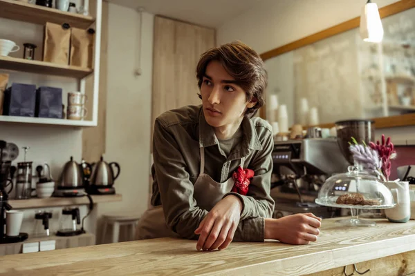 Thoughtful young guy working as barista in coffee place