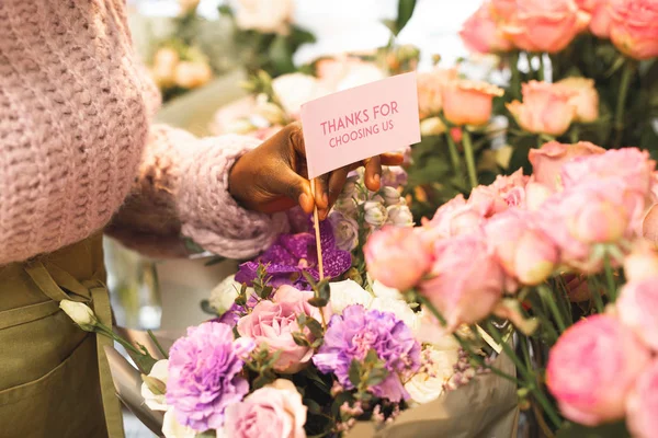 El primer plano de la mano femenina que pone la tarjeta en el ramo — Foto de Stock