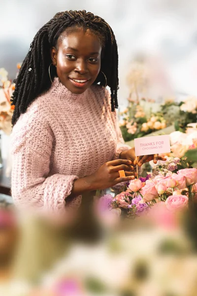 Симпатичный международный продавец рядом с цветами — стоковое фото