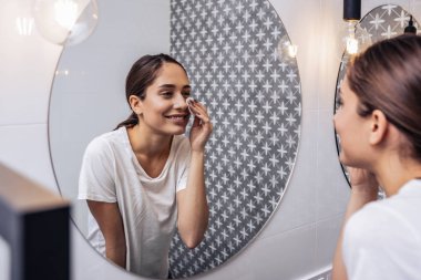 Gülümseyen kadın uyumadan önce makyajını çıkarıyor