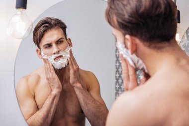 Yüzünü tıraş etmek için hazırlanan ciddi adam