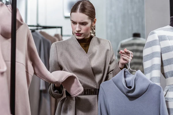 Geconcentreerde vrouw die goed kijkt naar kleding in de winkel — Stockfoto