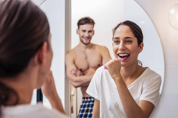 Веселая женщина чистит зубы перед своим парнем — стоковое фото