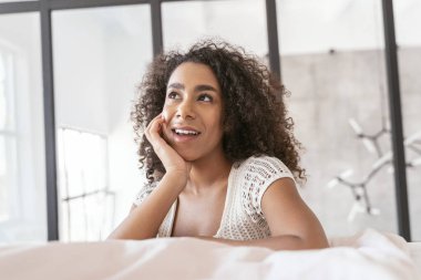 Neşeli genç bir kadın çenesini eline dayıyor.