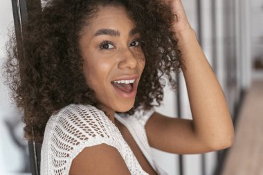 Kamerada poz veren neşeli kıvırcık saçlı kız.