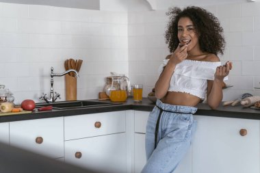 Güzel kadın yemek pişirirken atıştırıyor.
