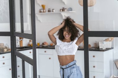 Mutfağının girişinde duran mutlu bayan.