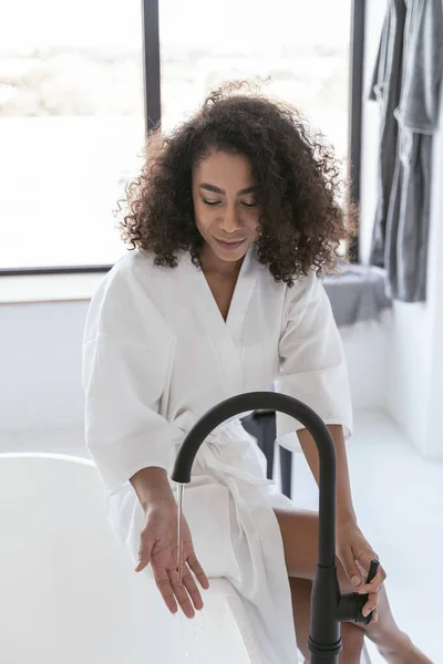 Hermosa mujer joven comprobando el agua caliente — Foto de Stock