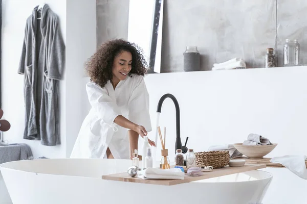 Mujer comprobando la temperatura del agua corriente — Foto de Stock