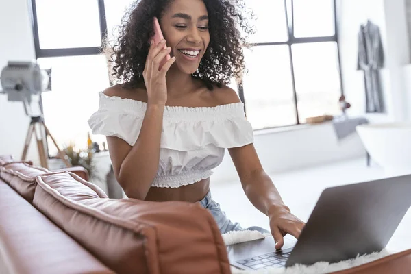 Fröhliche Frau, die arbeitet und mit ihrem Freund spricht — Stockfoto