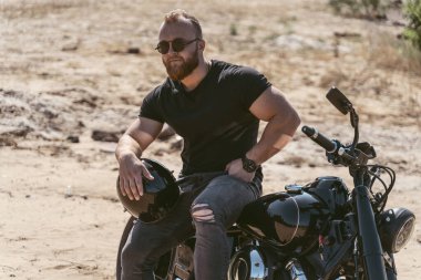 Kasklı, bisiklette poz veren vahşi çekici bir erkek.