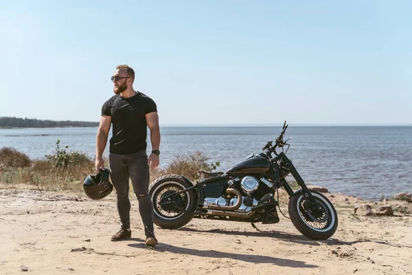 Motociclista atlético fresco de pie junto a su bicicleta —  Fotos de Stock