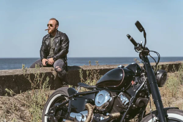 Beau barbu avec sigar assis au bord de la route regardant au-dessus de l'océan — Photo