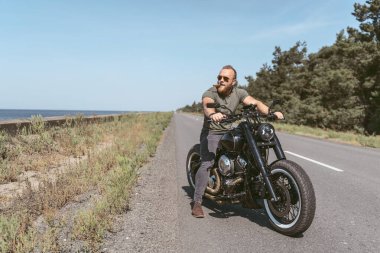 Bisikletli seksi sporcu yolda oturuyor.