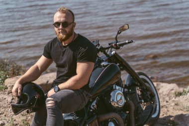 Bisikletinin üzerinde oturan yakışıklı kaslı motorcu.