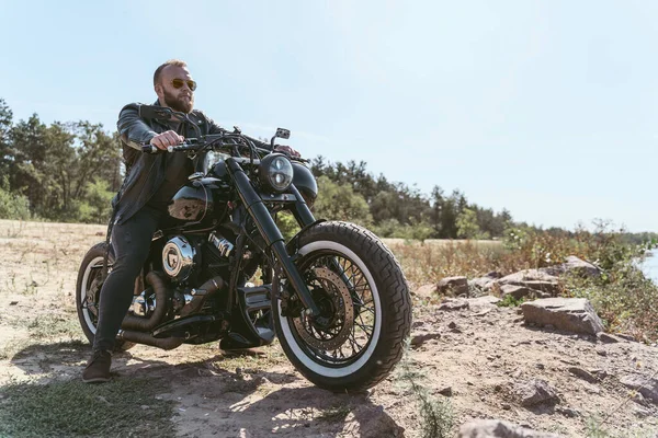 Beau motard barbu en veste en cuir assis sur son vélo — Photo