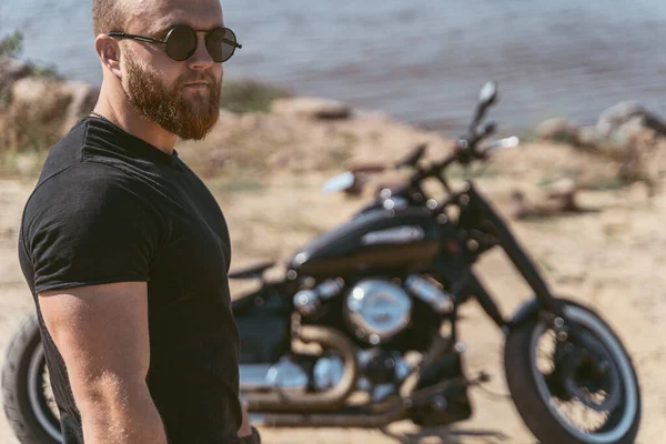 Bisikletinin önünde duran sakallı çekici bir adamın portresi.