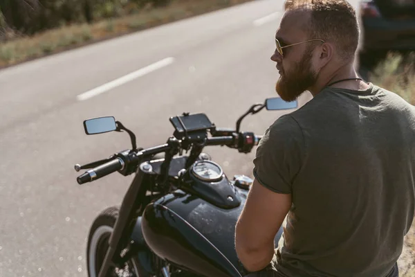 Visão traseira de um motociclista barbudo sentado em sua moto — Fotografia de Stock