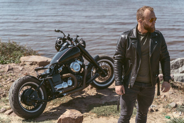 Confident attractive man looking to the side while posing next to his bike