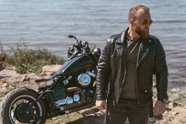 Красивый бородатый байкер позирует возле своего мотоцикла — стоковое фото