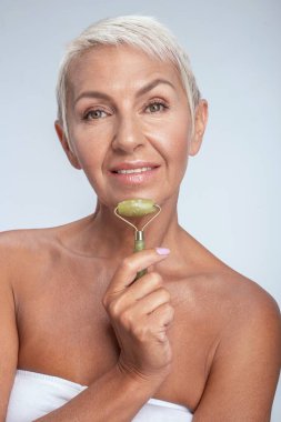 Güzel, yaşlı bir kadının portresi. Çenesine yeşim taşı takmış.