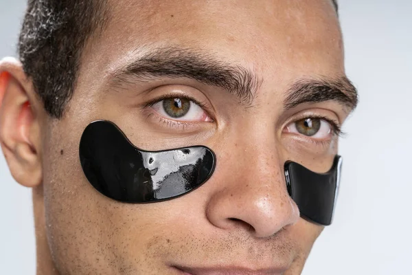 Young man moisturizing his under eye area — Stock Photo, Image