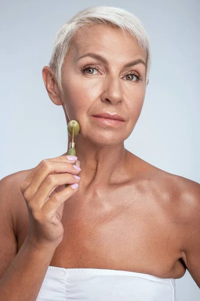 Mujer bastante saludable usando rodillo de jade en su cara — Foto de Stock