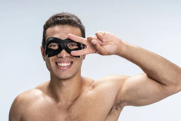 Jolly young man trying new skin care — Stock Photo, Image