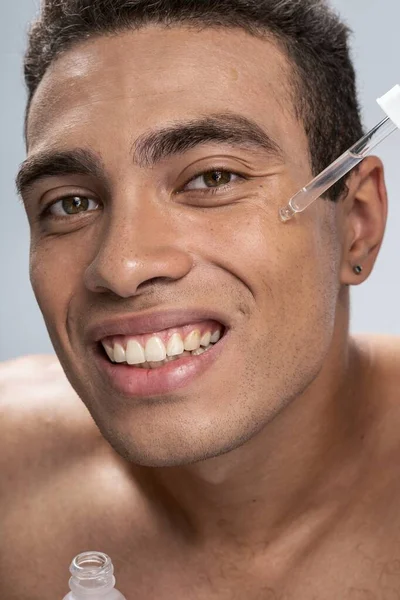 Усміхнений чоловік одягає свій новий косметичний продукт — стокове фото