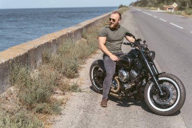 Yolun kenarında oturan seksi kaslı motorcu.