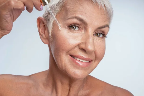 Положительный восторг пожилая женщина делает косметические процедуры — стоковое фото