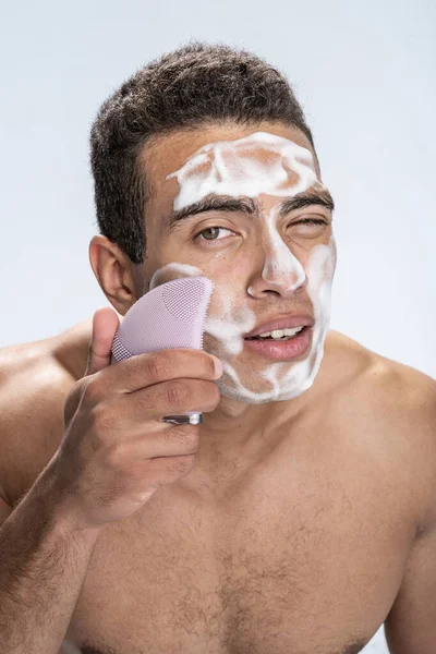 Focused young man scrubbing his problem skin — Stock Photo, Image