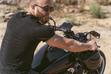 Bisikletinde oturan formda ve kaslı bir motorcunun arkadan görünüşü