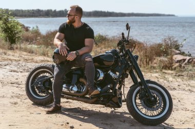 Bisikletin üstünde oturan yakışıklı, vahşi bir motorcu.