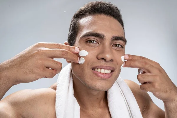 Un bel homme qui protège sa peau avec une crème. — Photo