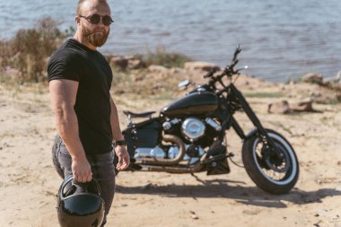 Bisikletin yanında duran kasklı yakışıklı motorcu.