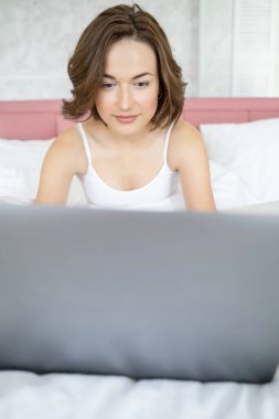 Dizüstü bilgisayarının önünde oturan gülümseyen kadın.