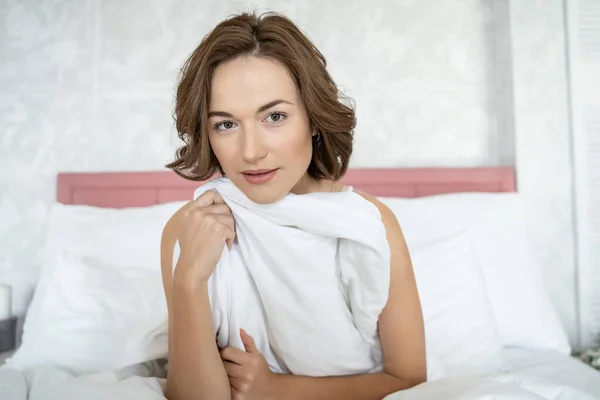 Uvolněná mladá žena sedí ve své posteli — Stock fotografie