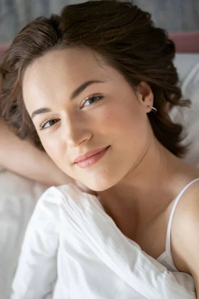 Mujer linda en la cama sonriendo a la cámara — Foto de Stock