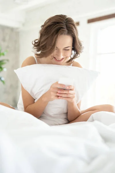 Atractivo feliz joven dama mensajes de texto en la cama — Foto de Stock