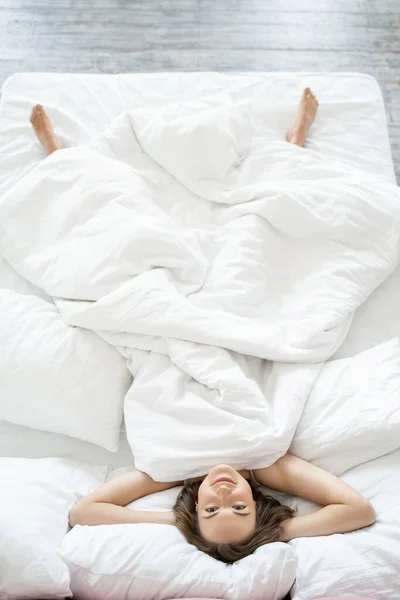 Nöjd ung dam som ligger på rygg i sängen — Stockfoto