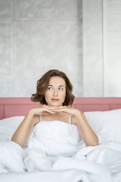 Linda joven mujer apoyando su barbilla en la cama — Foto de Stock