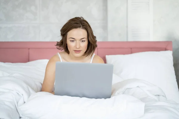 Mulher bonita trabalhando em seu laptop na cama — Fotografia de Stock