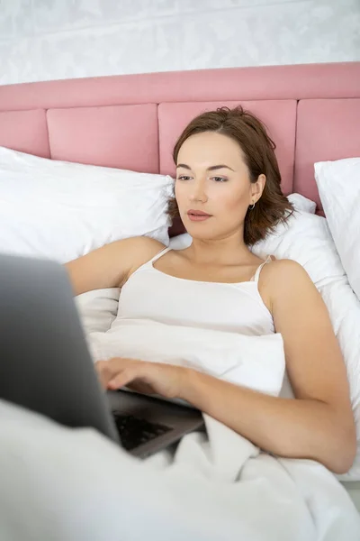 Menina digitando em seu laptop na cama — Fotografia de Stock