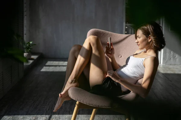 Señora con un smartphone en un sillón — Foto de Stock