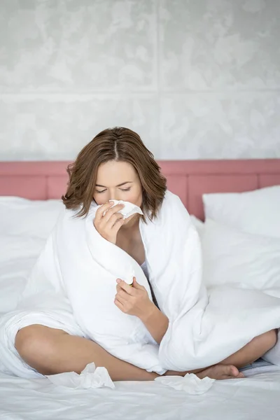 Mala mujer sonándose la nariz en la cama — Foto de Stock