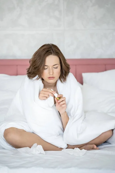 Mujer enferma con gotas nasales en la cama — Foto de Stock